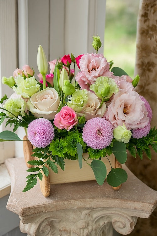 Pastel flower arrangement for a newborn baby girl in a handcrafted wooden pram, with roses, lisianthus, and chrysanthemums